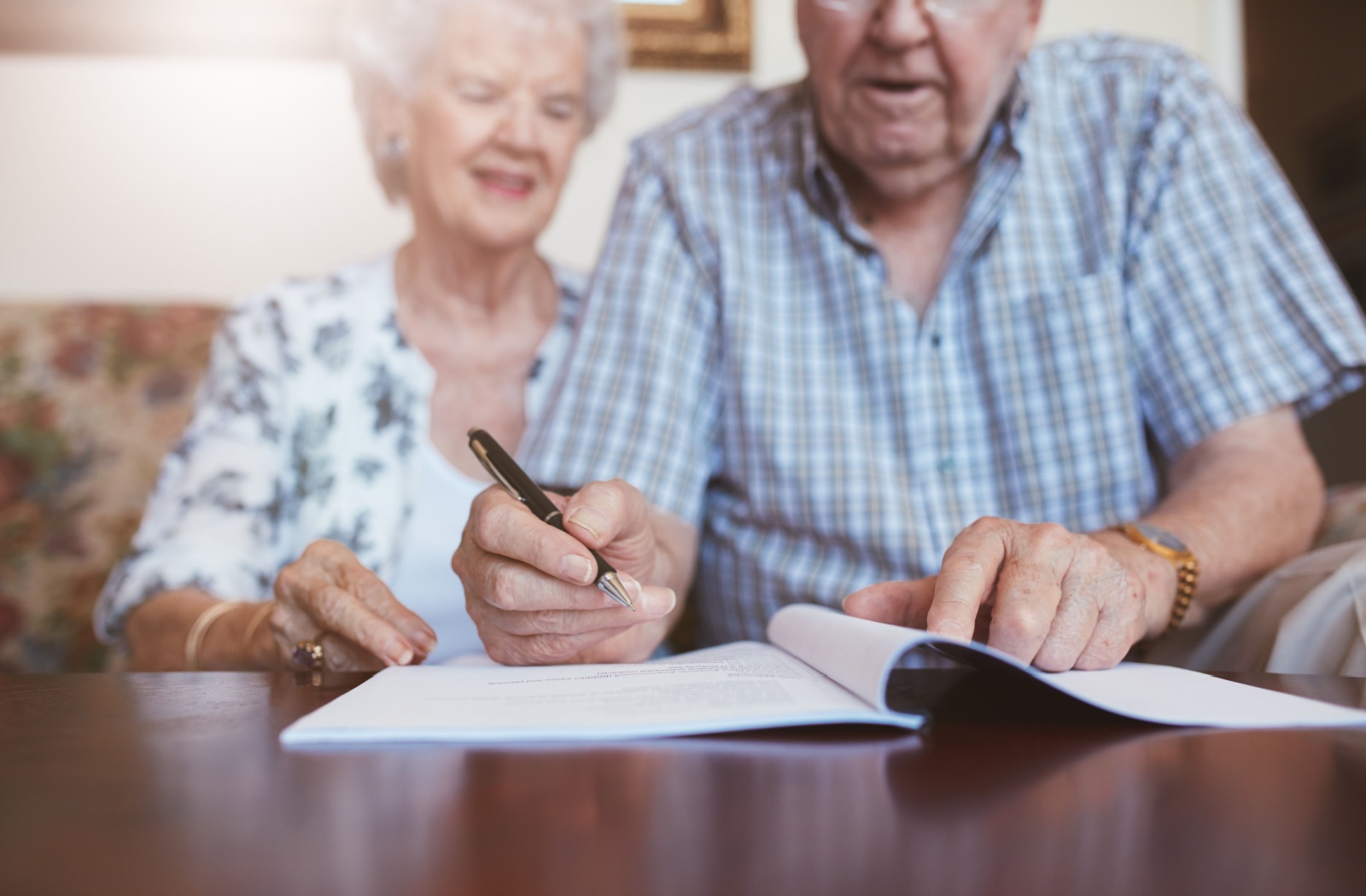 A senior couple sitting together getting ready to sign the terms of agreement to move into an assisted living community