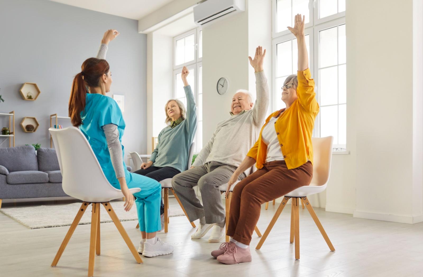 A caregiver leads a low-impact mobility exercise at a senior living community.