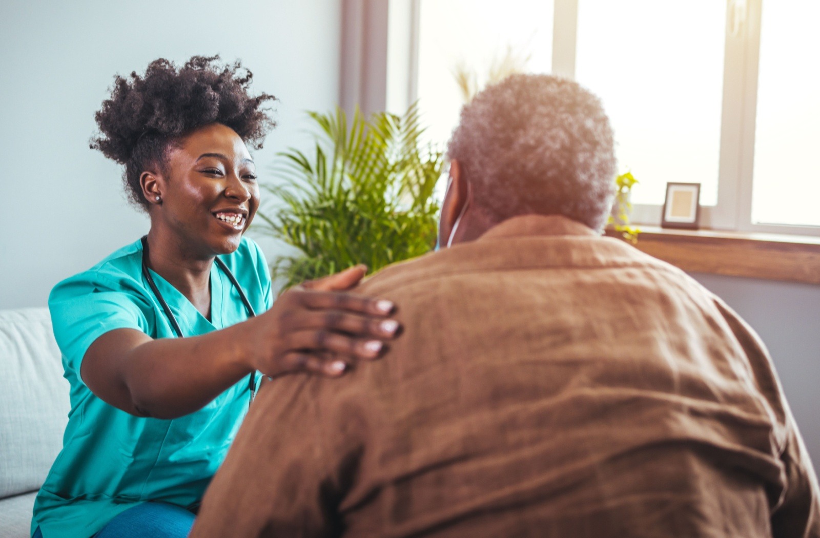 A smiling assisted living caregiver comforts a resident.